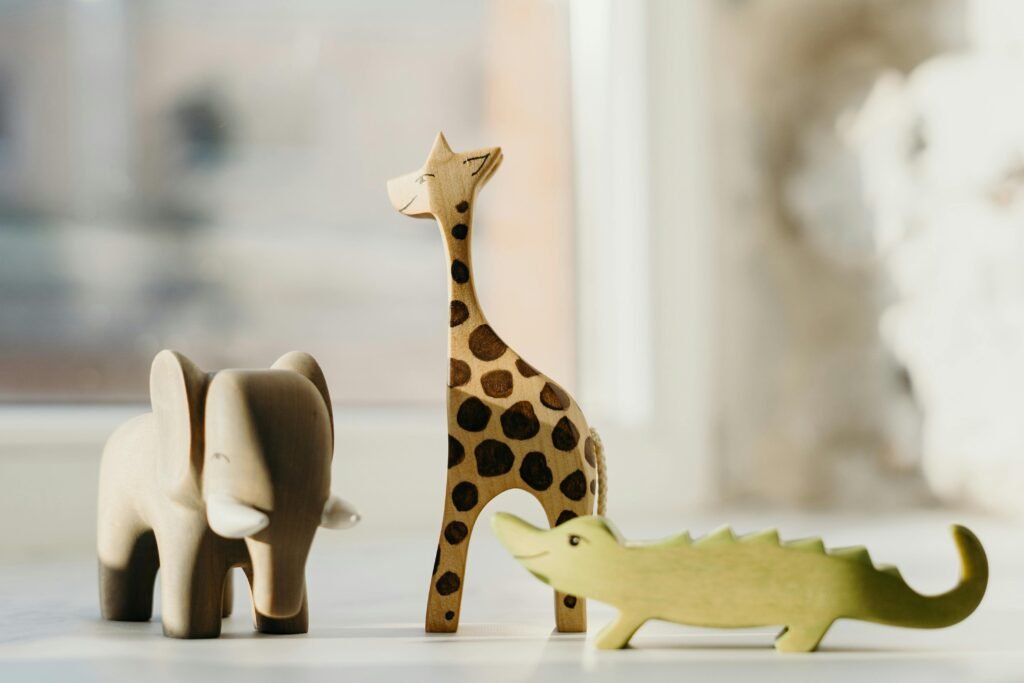 Wooden giraffe, elephant, and crocodile figures create playful decor. Ideal for kids' rooms.